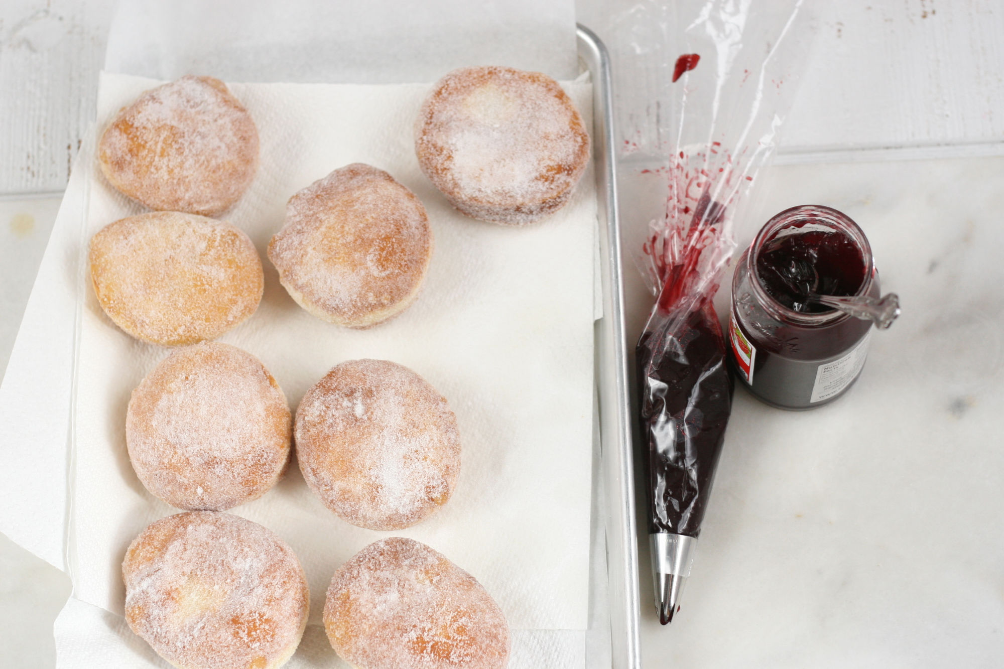 filling homemade donuts with raspberry jam.