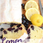 Partially sliced lemon blueberry loaf cake, slices of lemons on wooden cutting board.