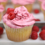 Lemon cupcake with raspberry frosting and fresh raspberries around it