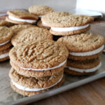 Oatmeal cream pies stacked on top of each other on a sheet pan