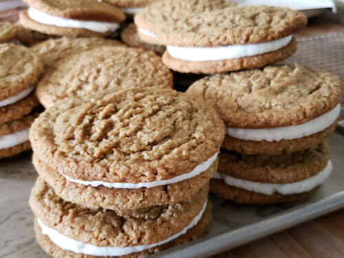 Oatmeal cream pies stacked on top of each other on a sheet pan