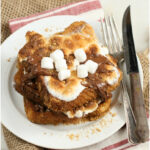 stacks of S'mores French Toast on white plate with fork and knife to the right