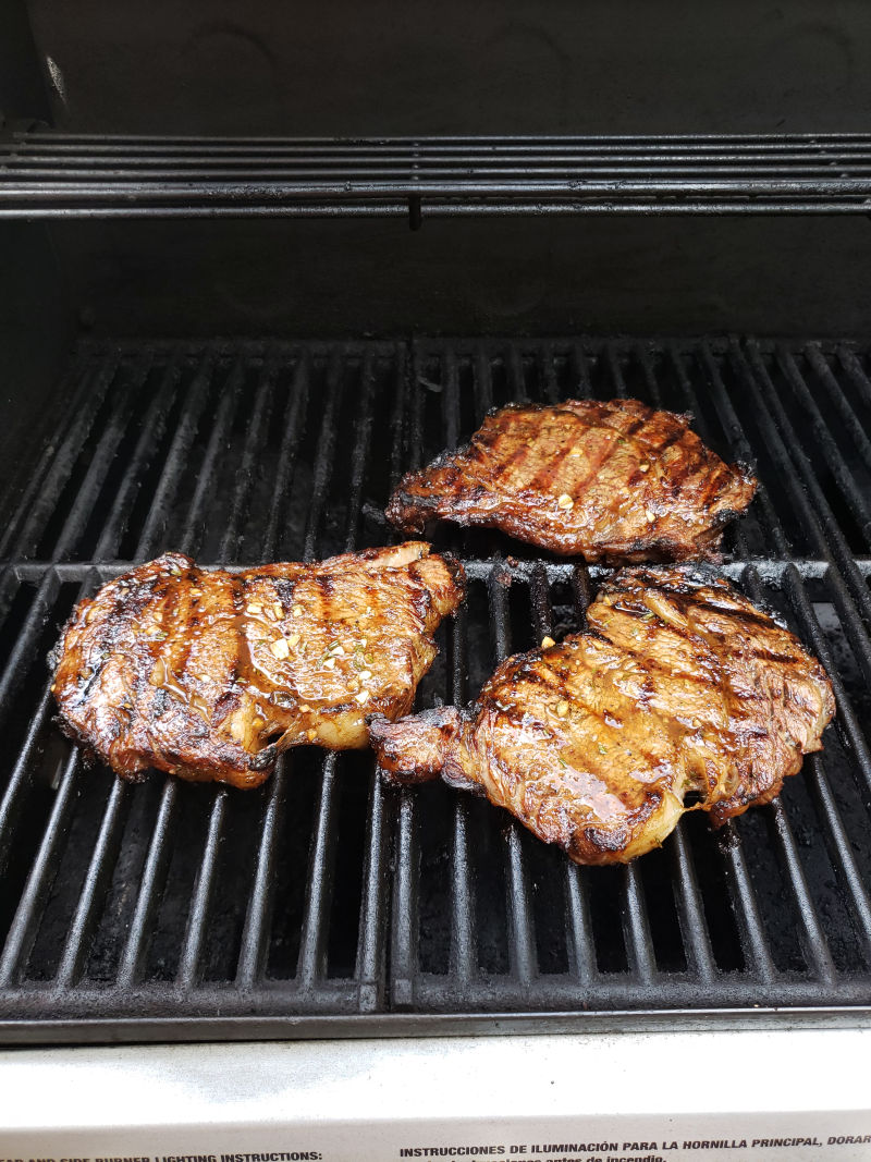 juicy steak on gas grill with browned grill marks.