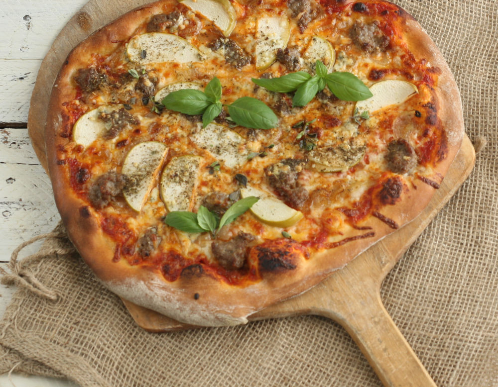 Italian-style pizza with slices of granny smith apples, cheese, and sausage.