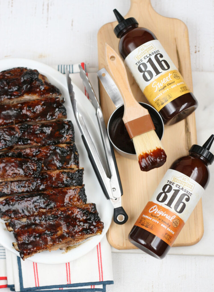 Barbecue pork ribs basted with barbecue sauce on plate with tongs