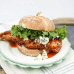 Buffalo fried chicken sandwich on small white plate.