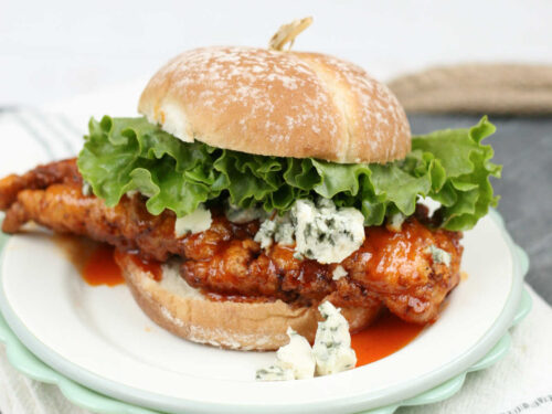 Buffalo fried chicken sandwich on small white plate.