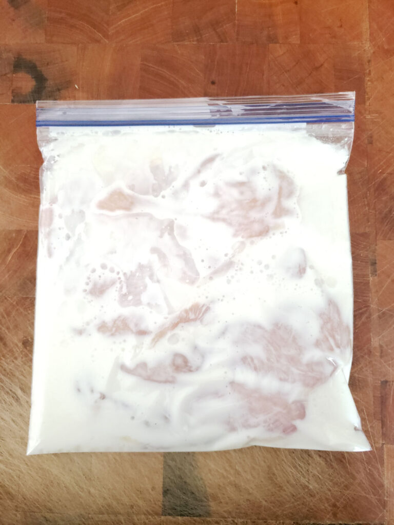 boneless skinless chicken in a large zip style bag with buttermilk