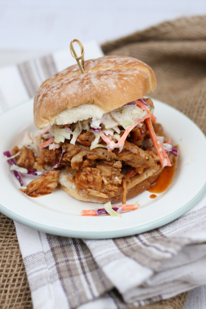 pulled pork sandwich on round roll and topped with coleslaw