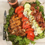 salad with chunks of grilled chicken, tomatoes, cucumbers, crispy bacon, and blue cheese
