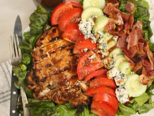 salad with chunks of grilled chicken, tomatoes, cucumbers, crispy bacon, and blue cheese