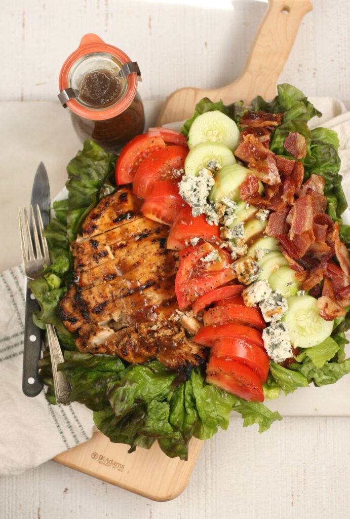 salad with chunks of grilled chicken, tomatoes, cucumbers, crispy bacon, and blue cheese