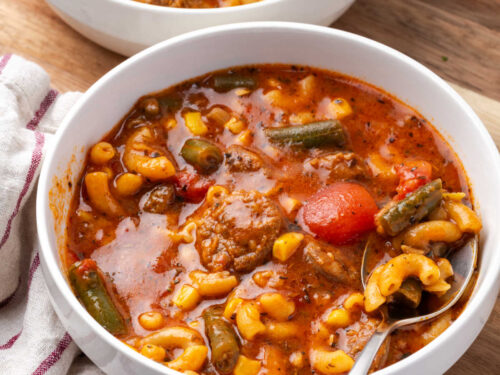 Soup with sausage, veggies and broth in bowl.