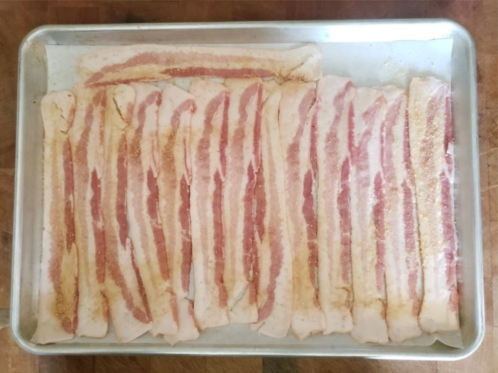bacon slices on a half sheet pan before baking in the oven