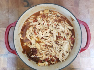 Mexican Shredded chicken in red Dutch oven on butcher block