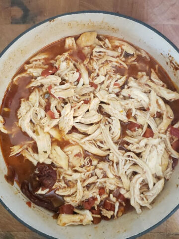 Mexican Shredded chicken in red Dutch oven on butcher block
