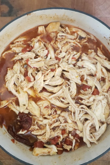 Mexican Shredded chicken in red Dutch oven on butcher block