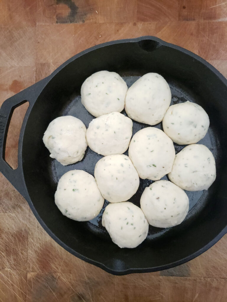 homemade dinner rolls rising in cast iron pan