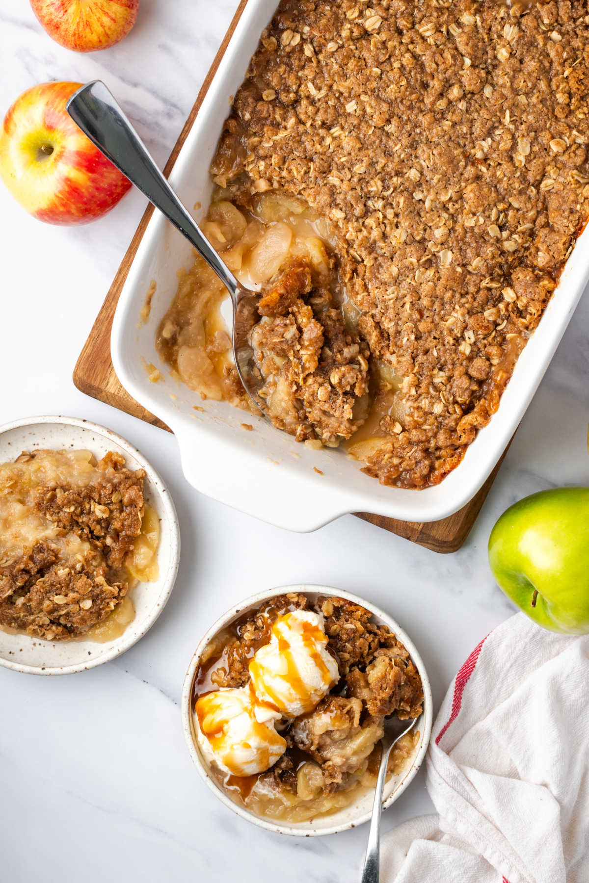 Serving spoon in white ceramic dish with apple crisp.
