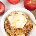 apple crisp in a bowl topped with vanilla ice cream