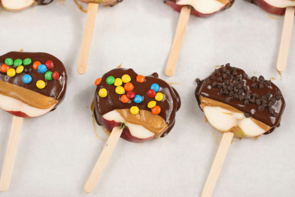 slices of apples on wooden sticks, dipped in caramel and chocolate