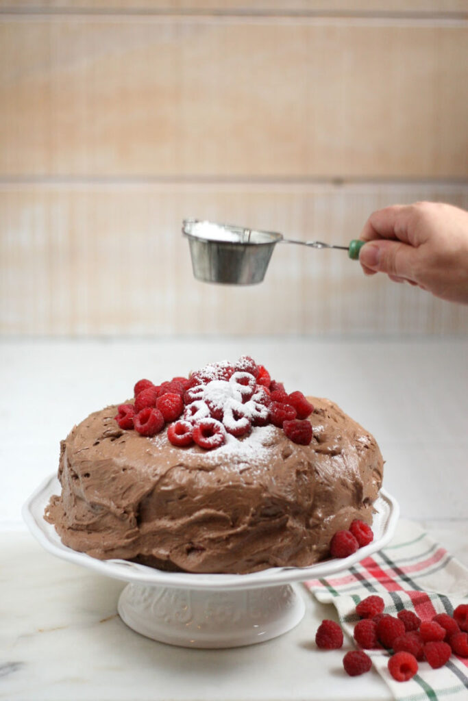 chocolate cake with raspberries, dusting top with powdered sugar