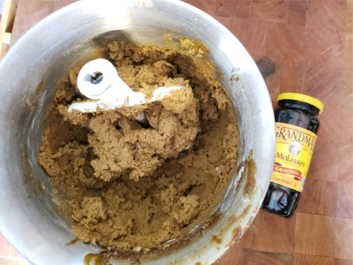 Molasses cookie dough in a mixing bowl on butcher block