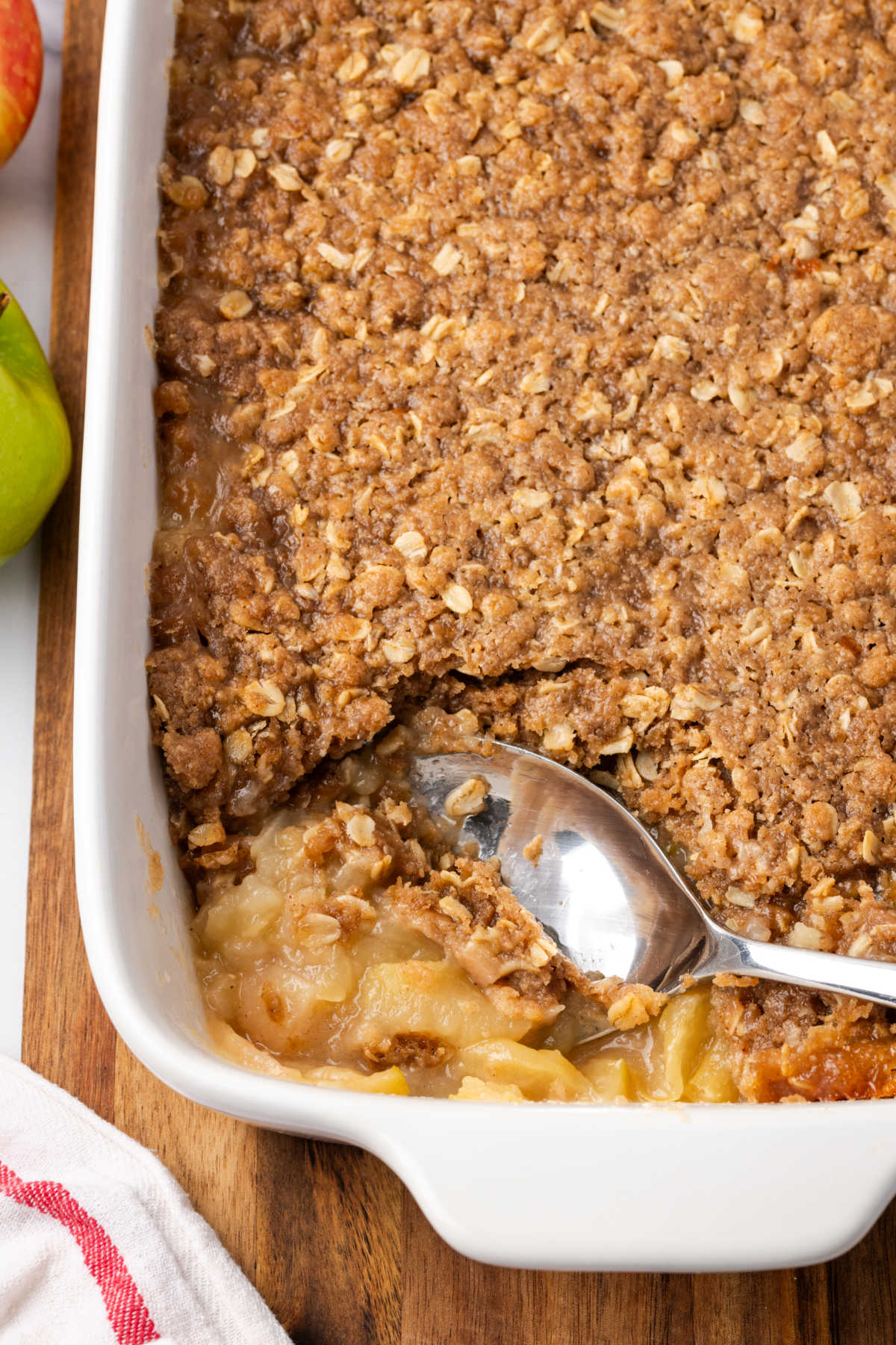 Close up of spoon in apple crisp in white baking dish.