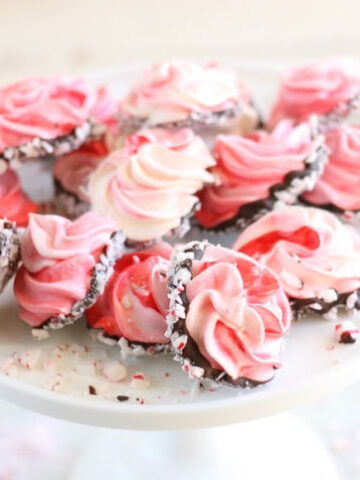 meringue cookies dipped in chocolate, rolled in crushed peppermints, on white footed cake dish