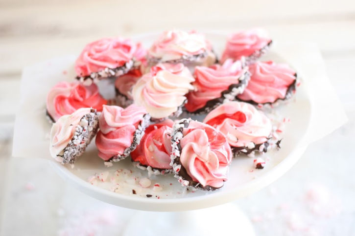 meringue cookies dipped in chocolate, rolled in crushed peppermints, on white footed cake dish