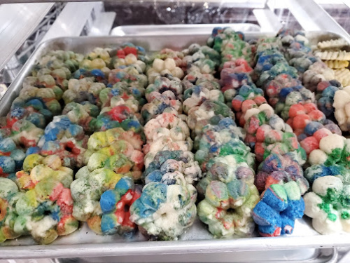 Colorful Spritz cookies lined up against each other on a half sheet pan