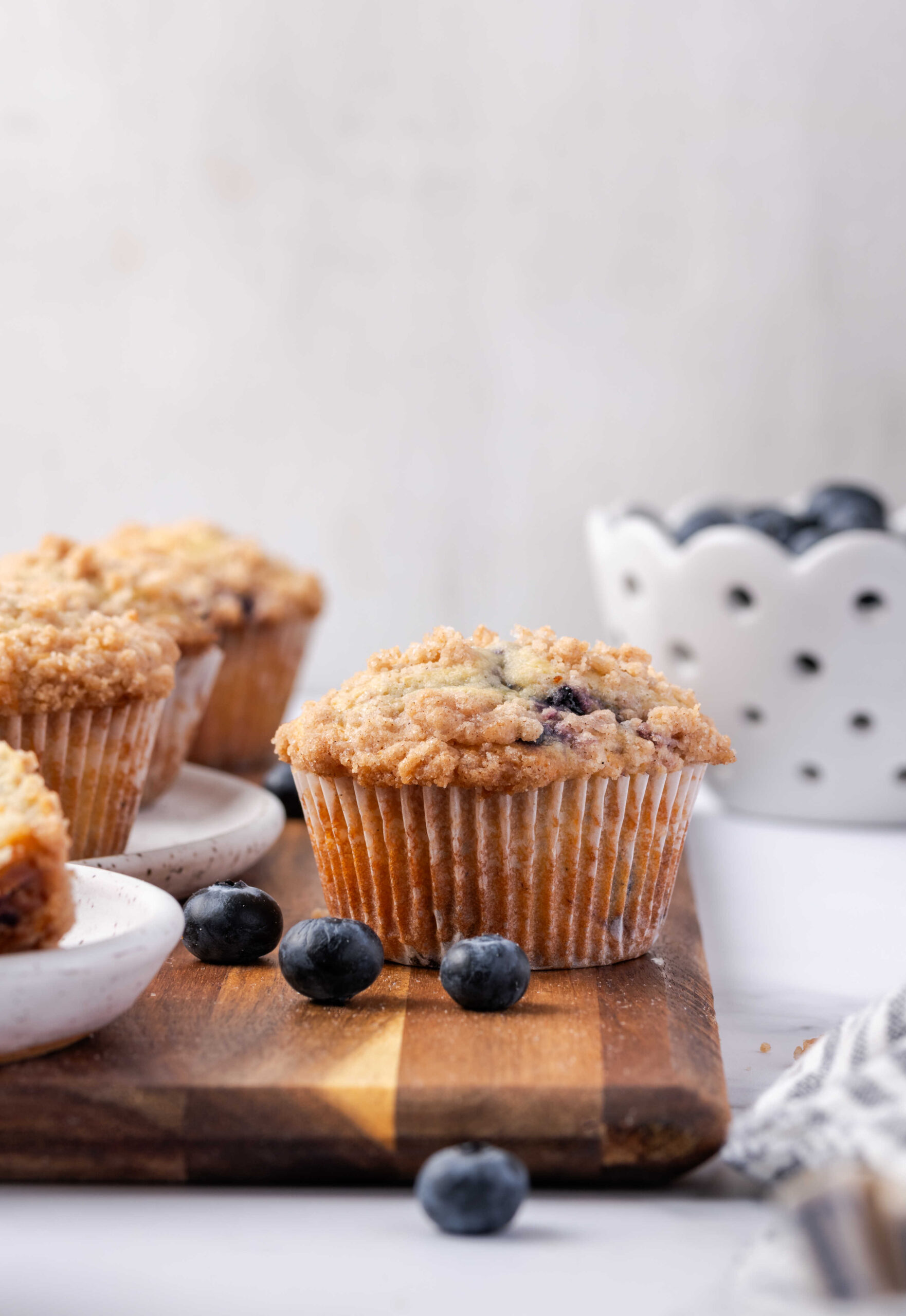 Blueberry muffins on wooden cutting board, fresh blueberries.