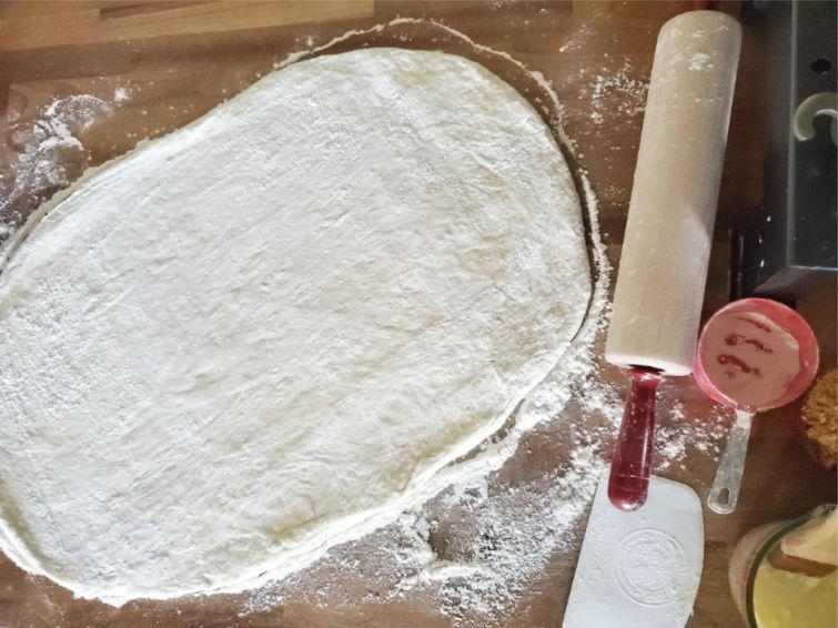 dough for cinnamon rolls rolled out on butcher block