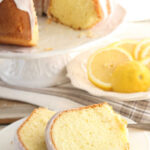 Lemon cake on white footed cake dish with slices of cake.