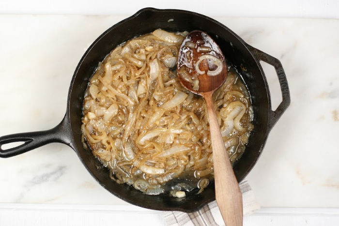 cast iron skillet with caramelized onions and wooden spoon