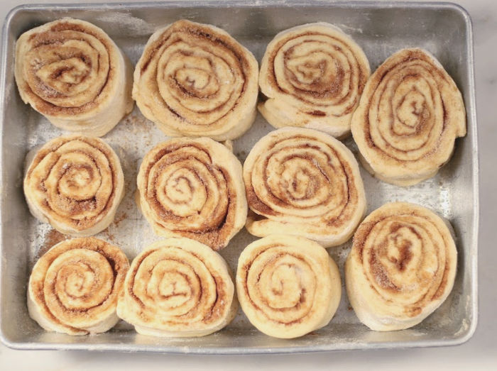 unbaked cinnamon rolls in a rectangle baking pan