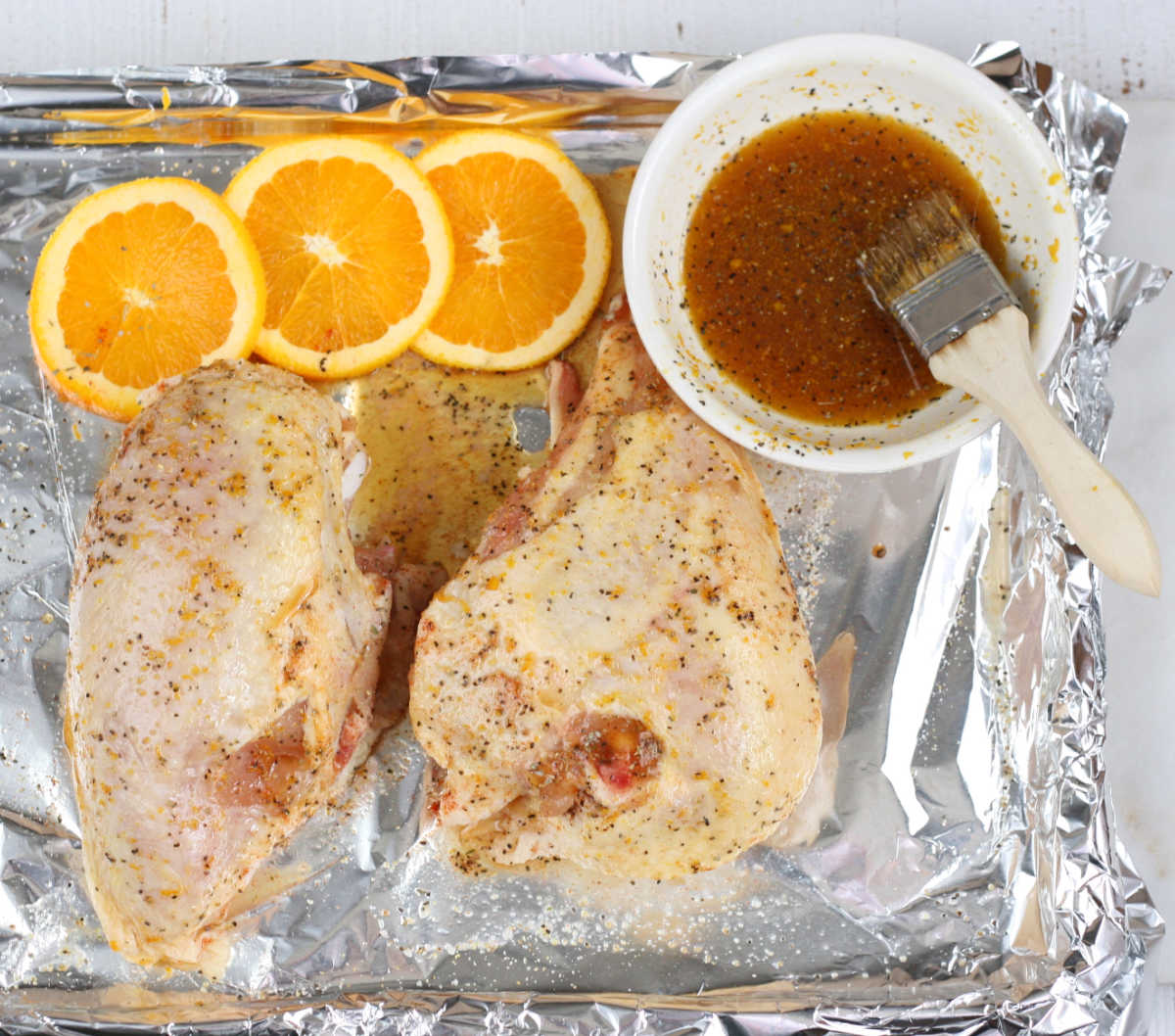 uncooked half chicken breasts on a half sheet pan lined with aluminum foil and seasonings.