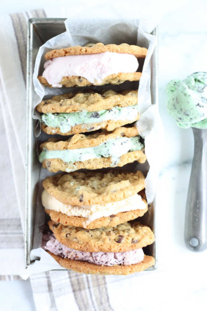 ice cream sandwiches stacked against each other in metal loaf pan, ice cream scoop with mint chocolate chip to right