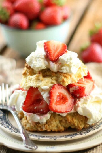 Sweet biscuits, strawberries and whipped cream on small white plate.