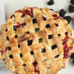 blackberry pie with lattice crust, fresh blackberries around it.