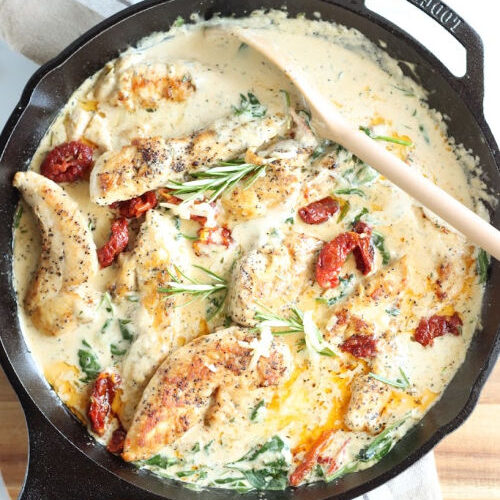 Chicken in cast iron skillet with sun dried tomatoes, spinach, and fresh rosemary