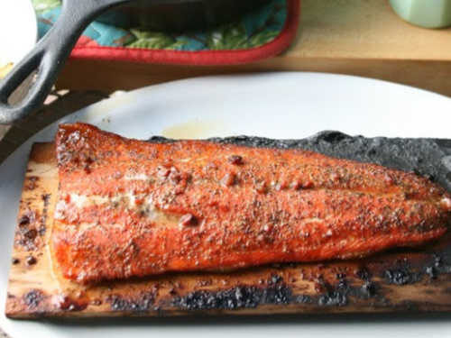 wild salmon grilled on cedar plank, on white oval serving plate
