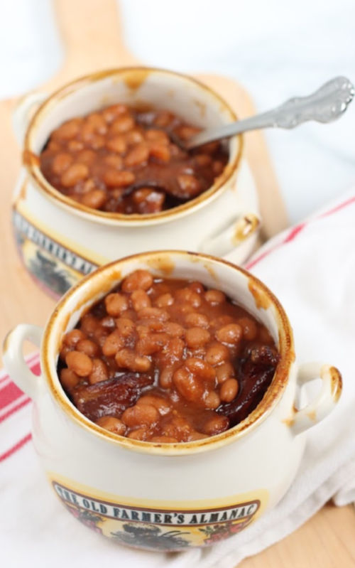 baked beans in small cream color crocks, sitting on wooden cutting board