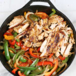 Chicken pieces, onions, Bell peppers in a large cast iron skillet.