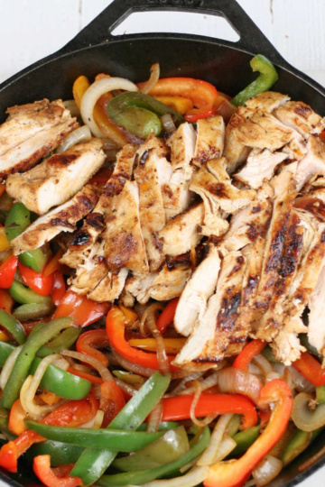 Chicken pieces, onions, Bell peppers in a large cast iron skillet.