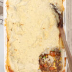 Shepherds pie in a white rectangle glass baking dish, scoop out of the right bottom corner