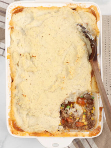 Shepherds pie in a white rectangle glass baking dish, scoop out of the right bottom corner