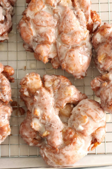 Close up of apple fritter donuts on baking rack.