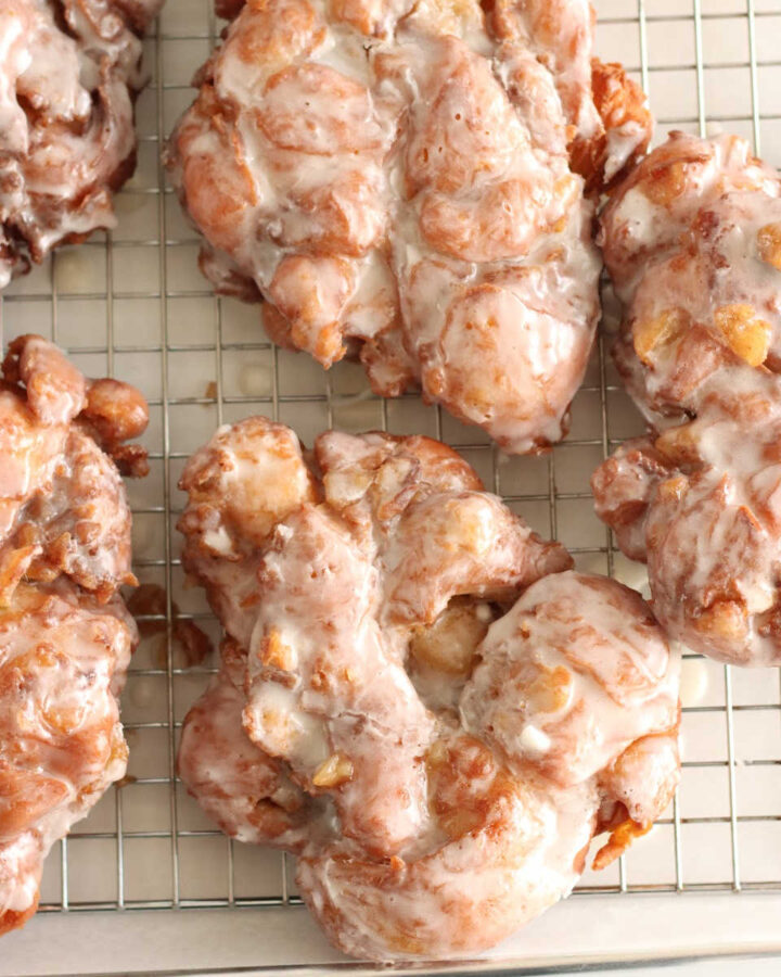 Close up of apple fritter donuts on baking rack.