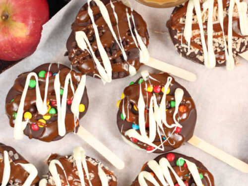 slices of apples on wooden sticks, dipped in chocolate, drizzled with caramel and white chocolate